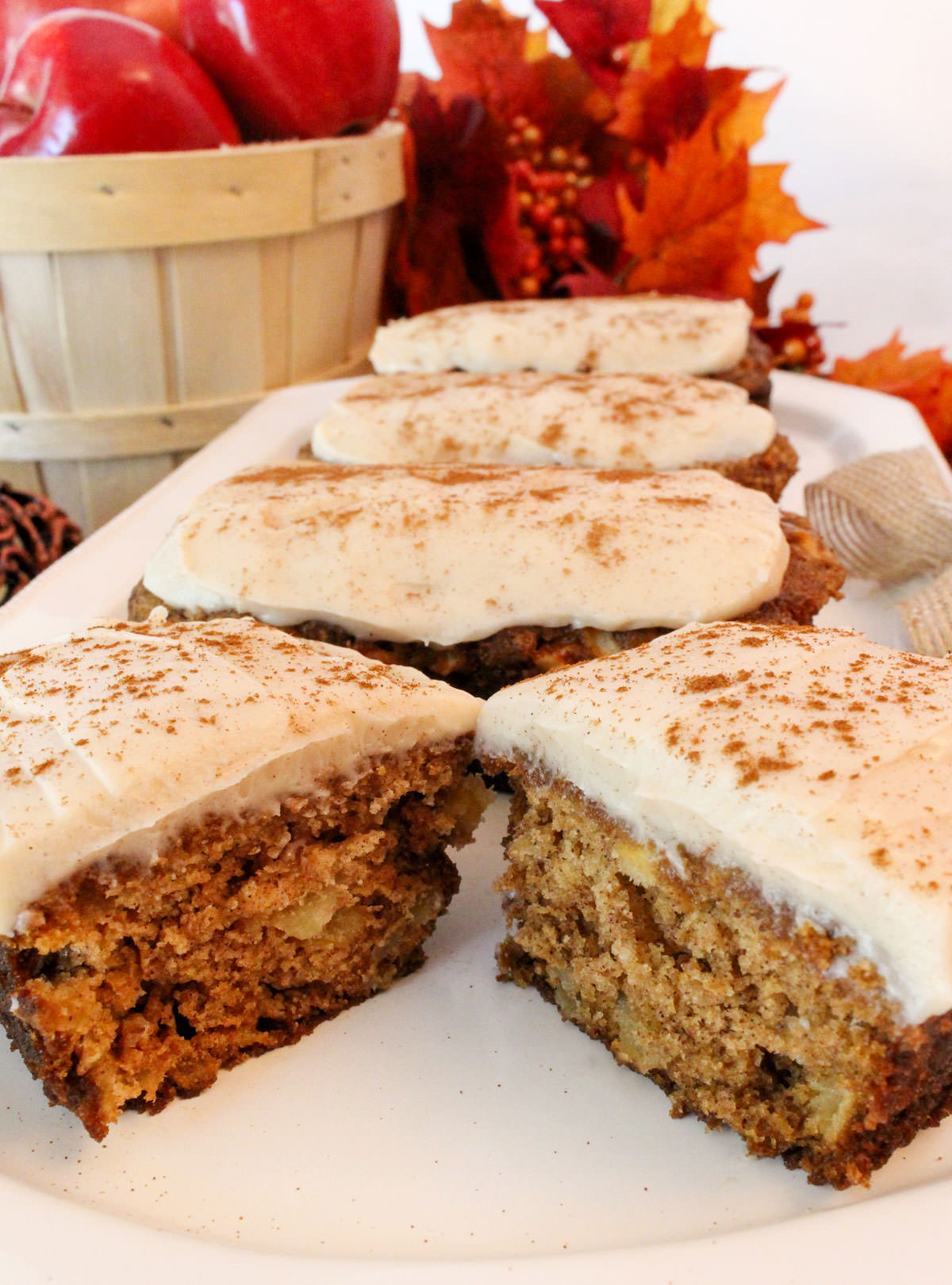 Closeup on a white serving platter filled with four Apple Bread Mini Loaves frosted with Cream Cheese Frosting.