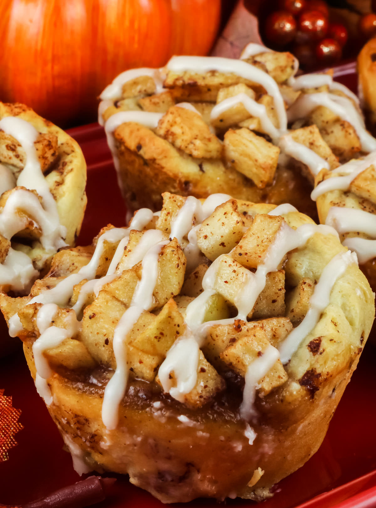 Closeup on three Easy Apple Cinnamon Rolls sitting on a red serving platter.