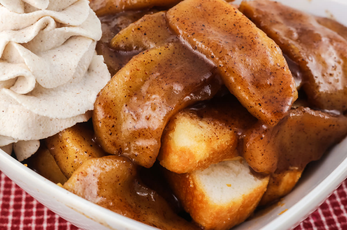 Closeup on a white bowl filled with angel food cake topped with Baked Apples with Cinnamon Whipped Cream.