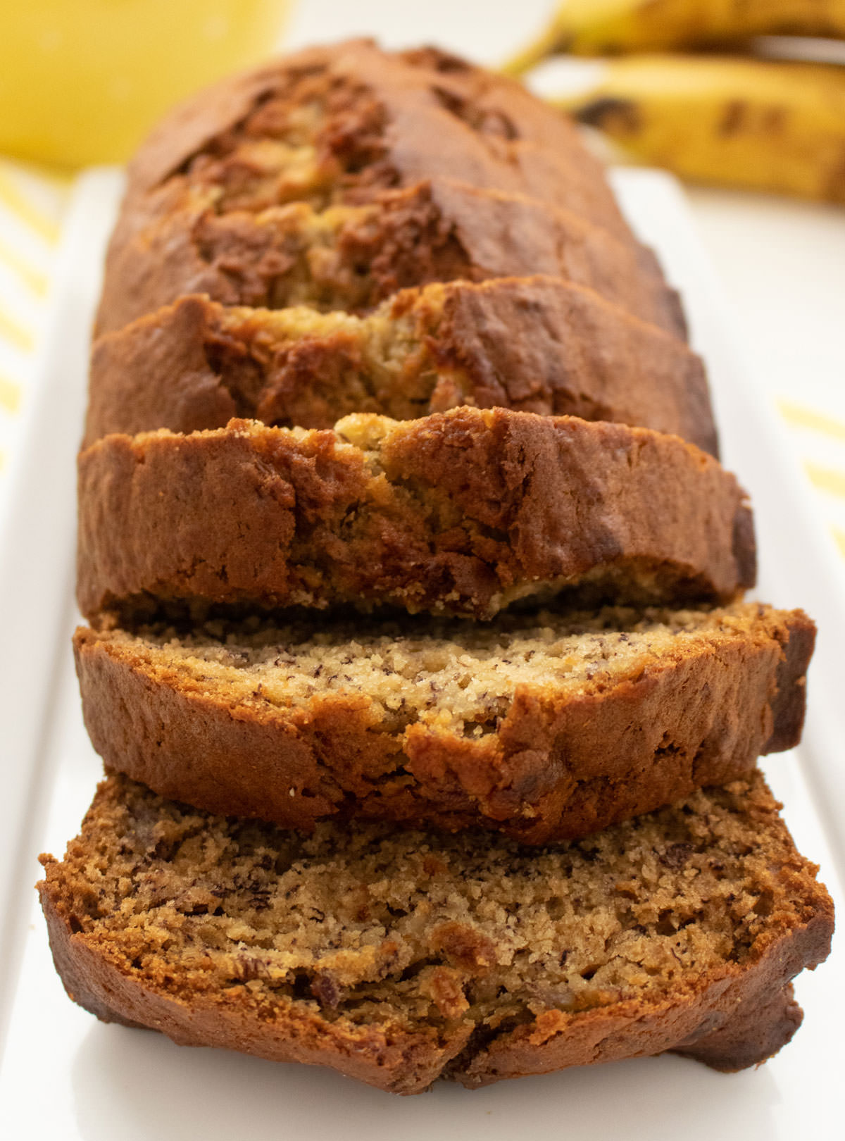 Closeup on a loaf of homemade Banana Bread, sliced into pieces, arranged on a serving platter.