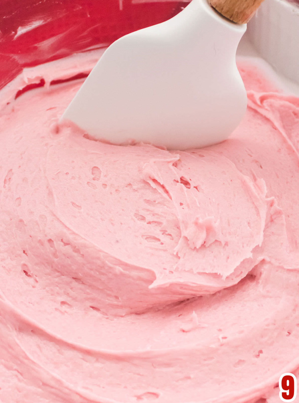 Closeup on a batch of Homemade Raspberry Frosting in a glass bowl. 