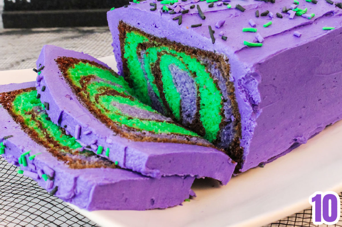 Closeup on a Halloween cake sitting on a white serving platter with slices cut to show the marble effect on the inside of the cake.