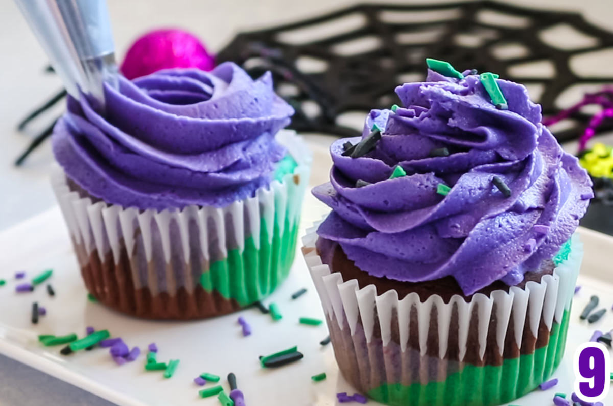 Closeup of two Bewitched Marble Cupcakes on a white serving platter, one is having the buttercream frosting swirled onto the top.