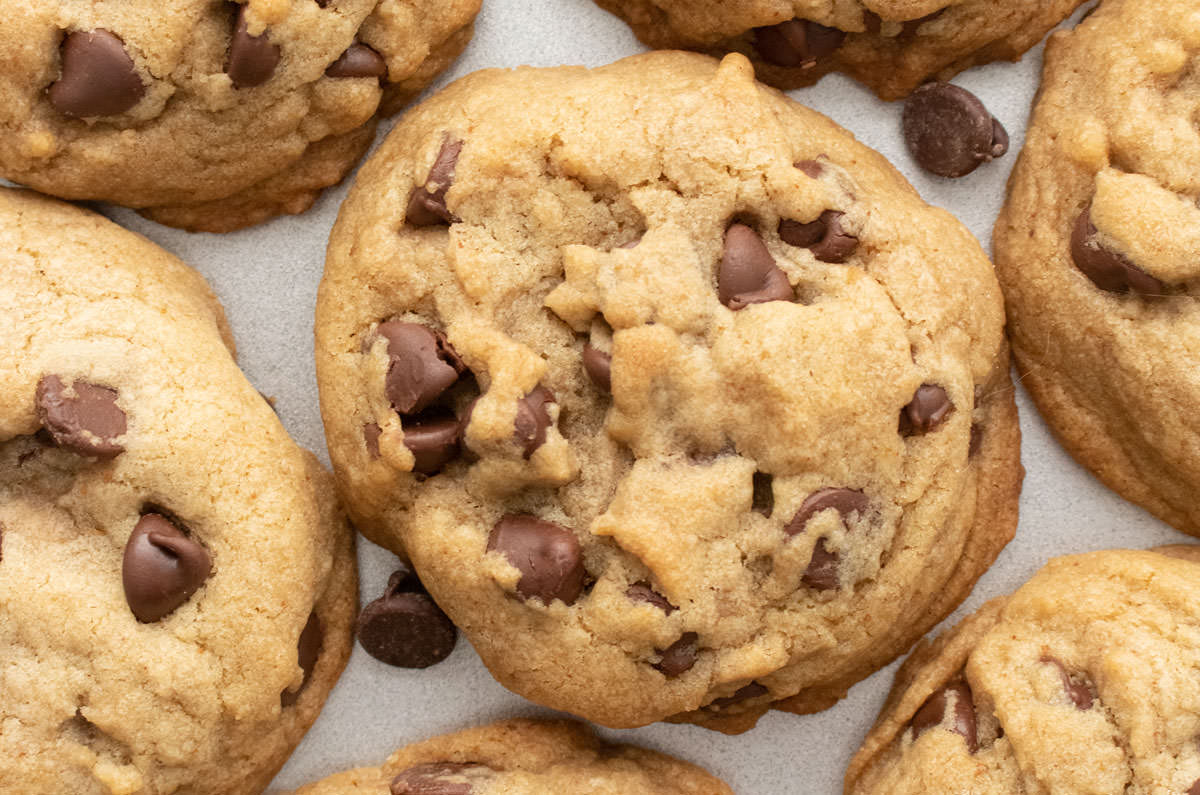 Closeup on a batch of Brown Butter Chocolate Chip Cookies laying on a silver cookie sheet.