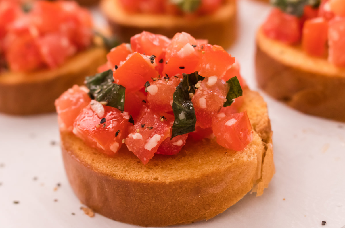 Close up of a piece of Italian Bruschetta sitting on a white surface.