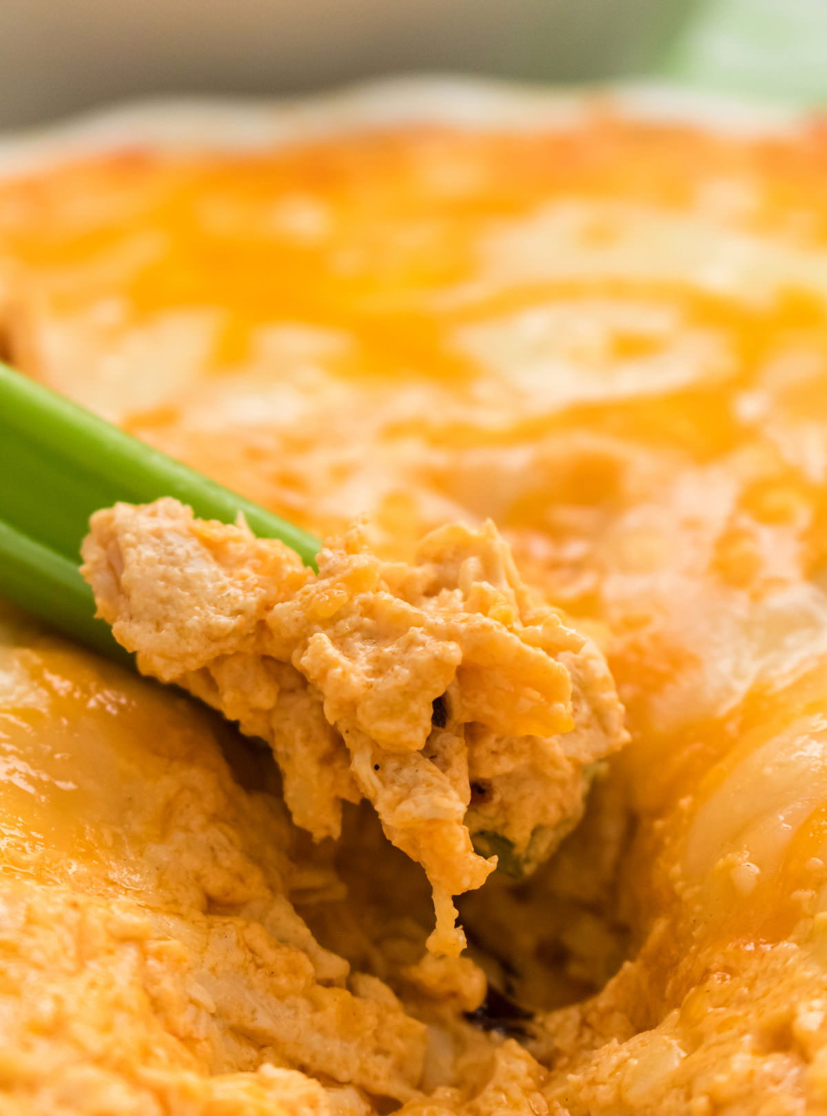 Closeup on a serving platter with Buffalo Chicken Dip with a celery stick dipped into the dip.
