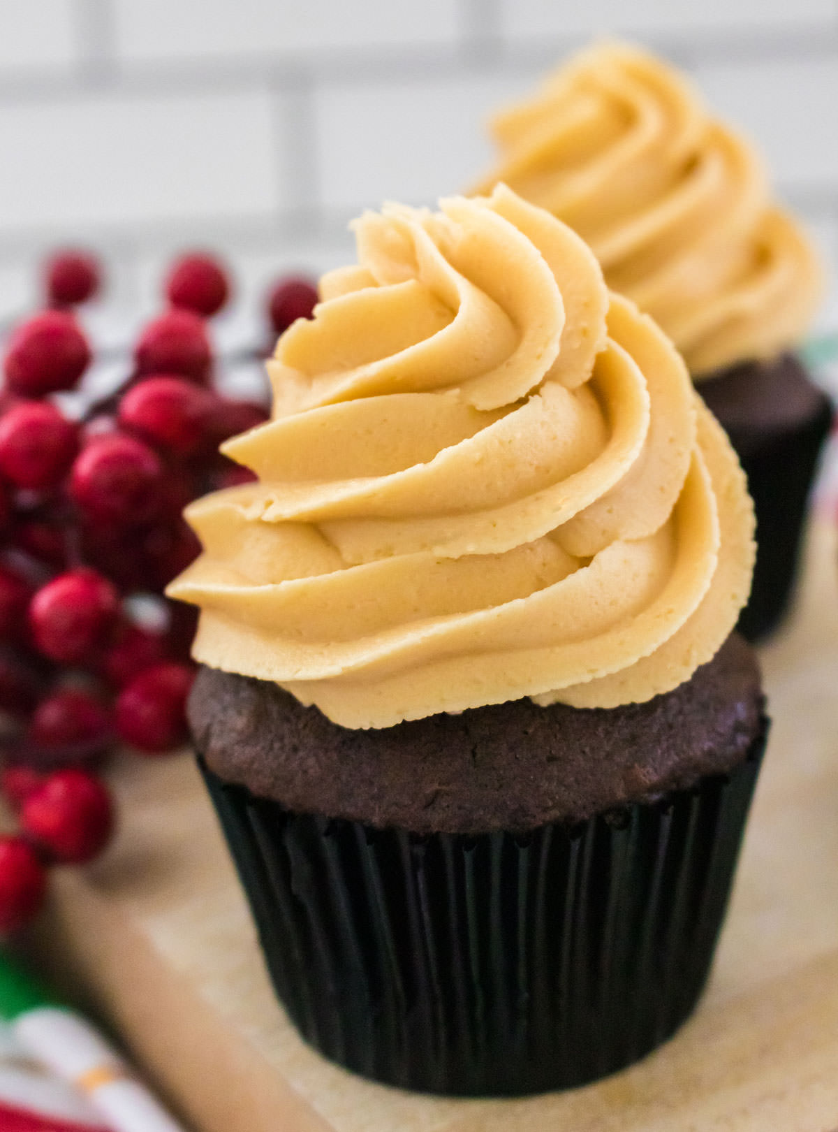 Closeup on a chocolate cupcake topped with The Best Butter Rum Buttercream Frosting sitting on a cutting board.