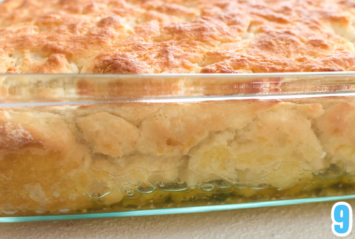 Closeup on a clear glass baking dish filled with Butter Swim Biscuits floating in a bed of melted butter.