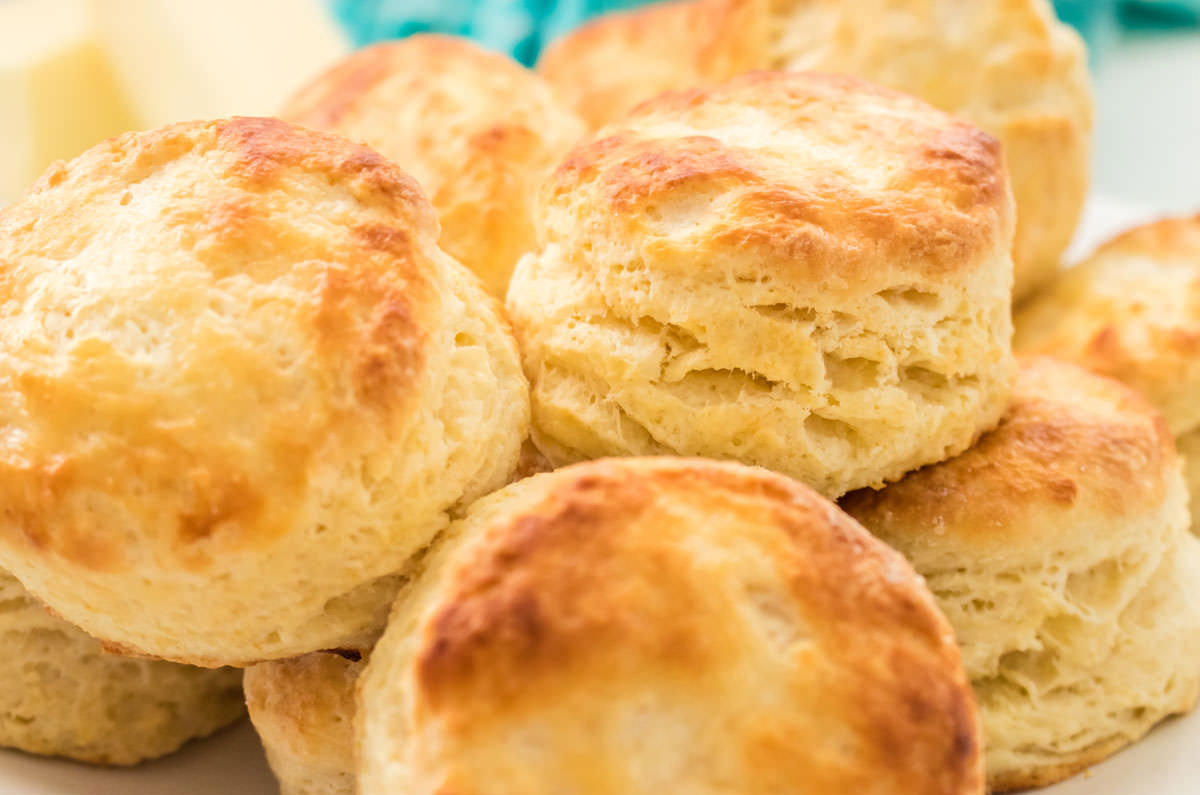 Closeup on a white serving bowl filled with a batch of homemade Buttermilk Biscuits.