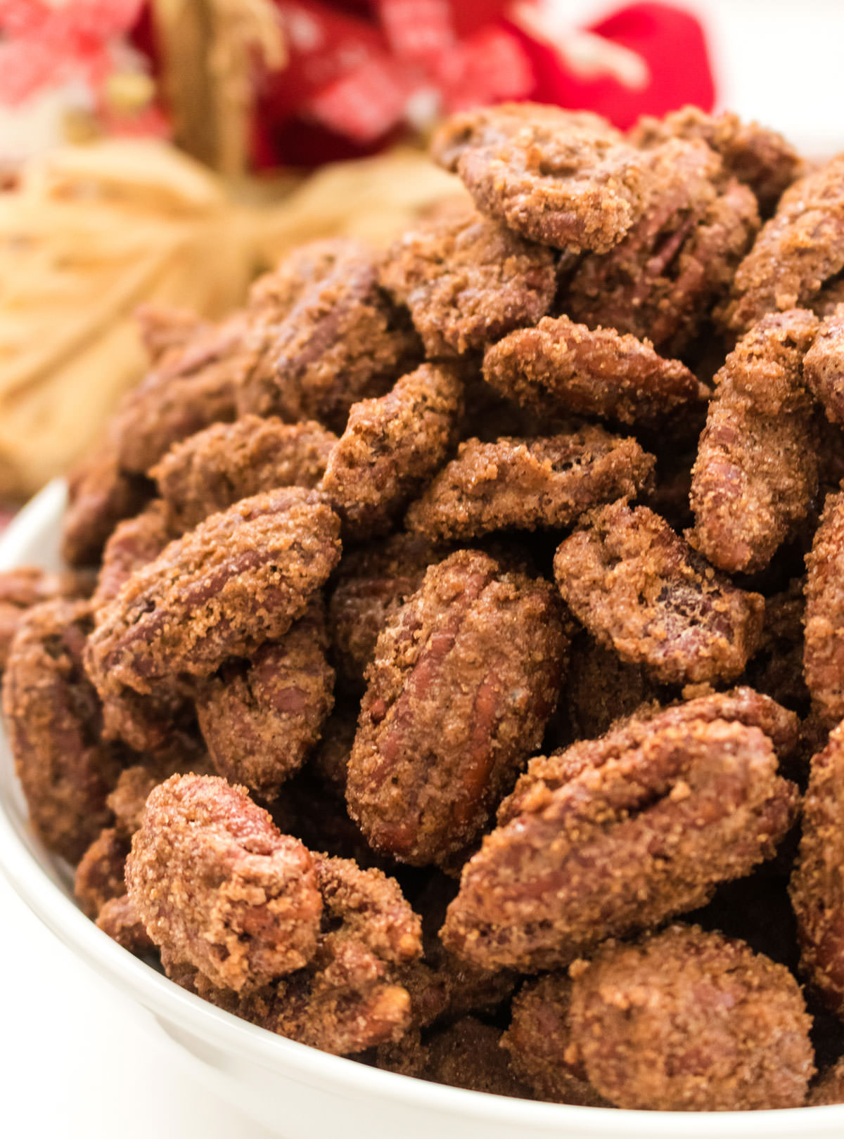 A close up of a bowl of Candied Pecans in a white bowl.