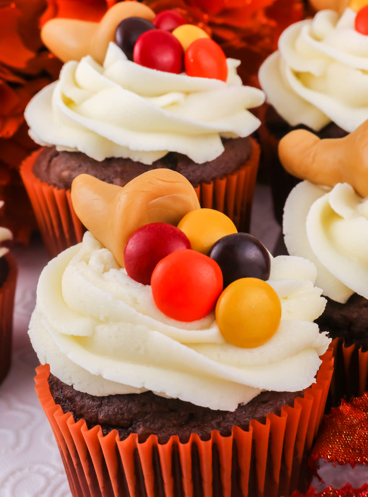 Closeup on a Caramelcopia Thanksgiving Cupcake sitting on a white surface surrounded by other cupcakes.