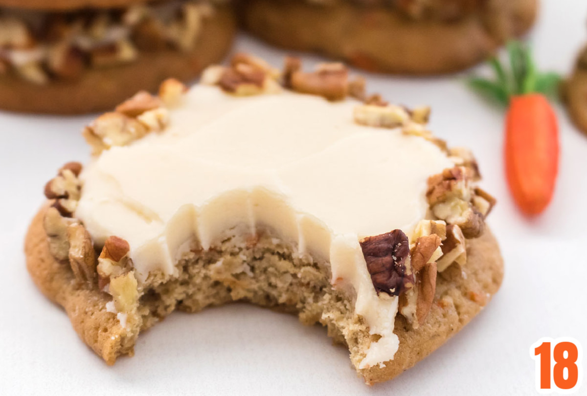 Closeup on a Carrot Cake Cookie frosted with Cream Cheese Frosting with a bite taken out of it.