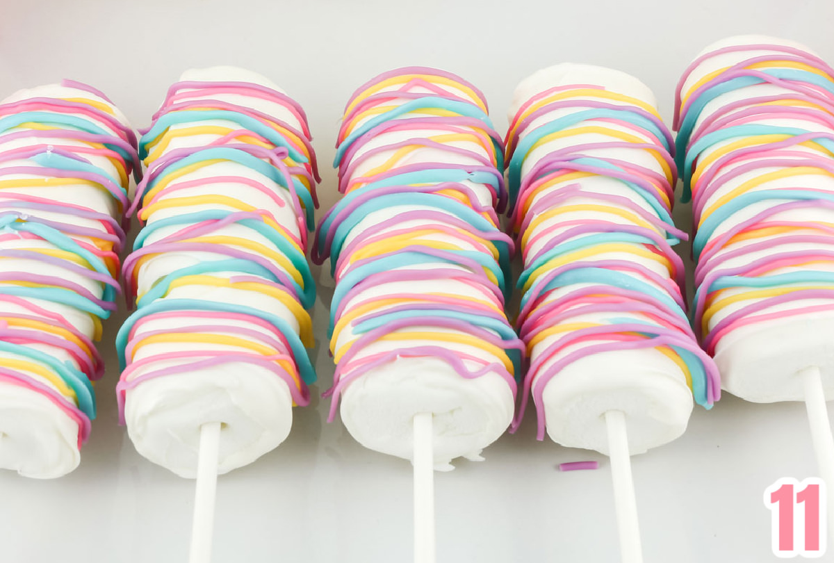 Close up on five Celebration Marshmallow Pops laying on a white serving platter.
