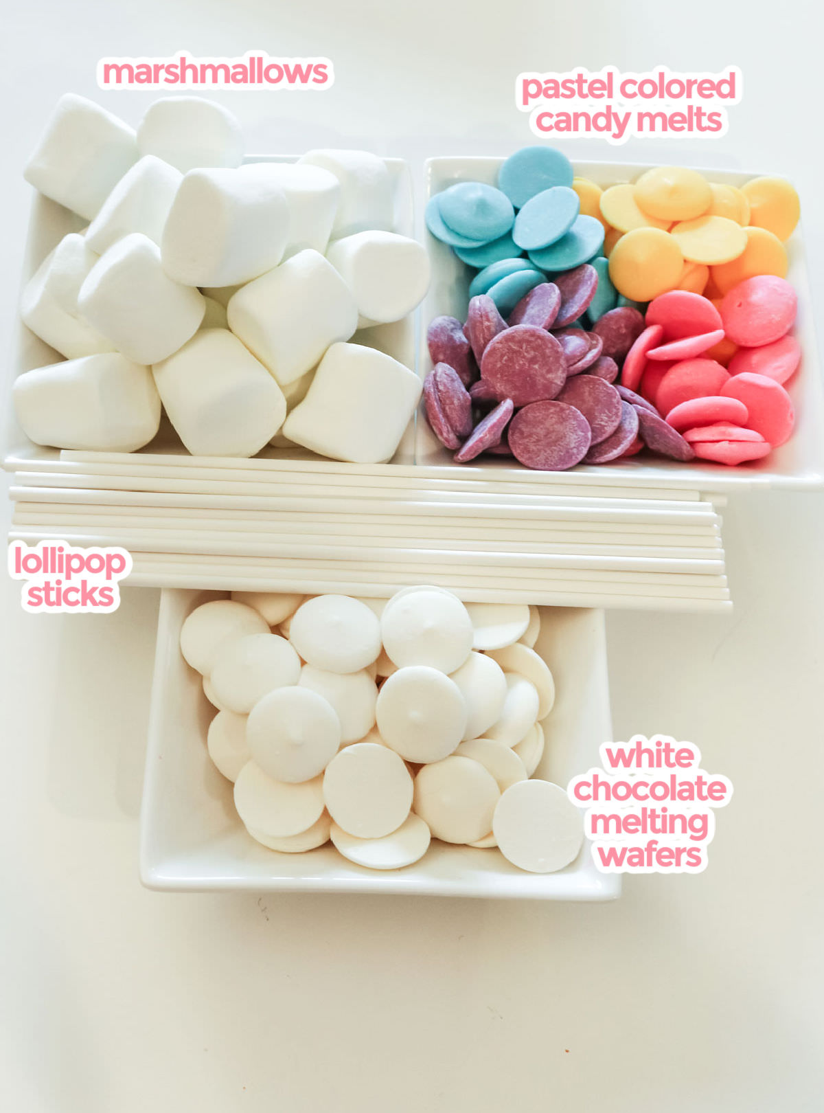 All the ingredients necessary to make Celebration Marshmallow Pops including marshmallows, lollipop sticks, white chocolate melting wafters and pastel colored candy melts.