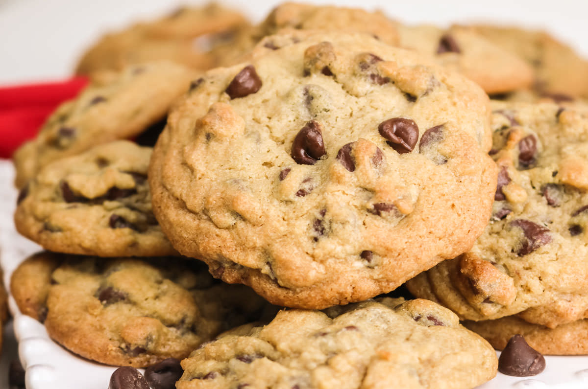 Closeup on a stack of Chocolate Chip Cookies sitting on a white dessert plate.