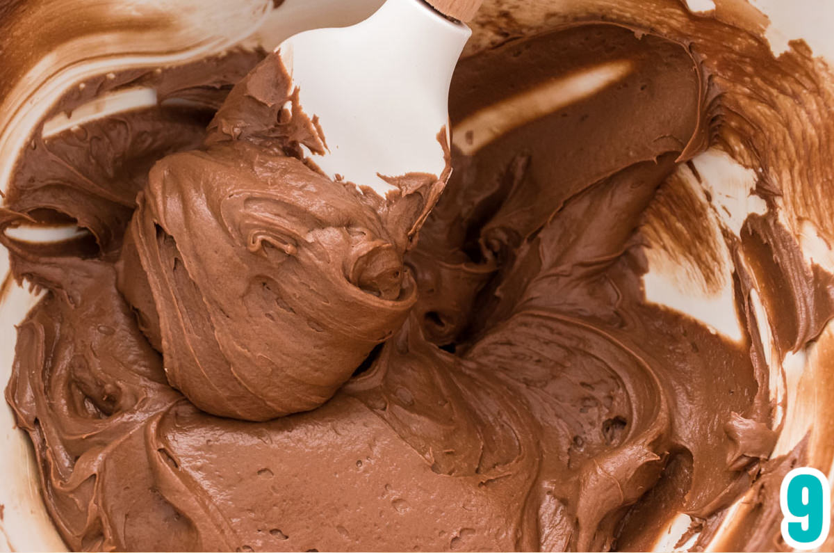 Closeup on a bowl of The Best Chocolate Cream Cheese Buttercream Frosting with a white spatula.