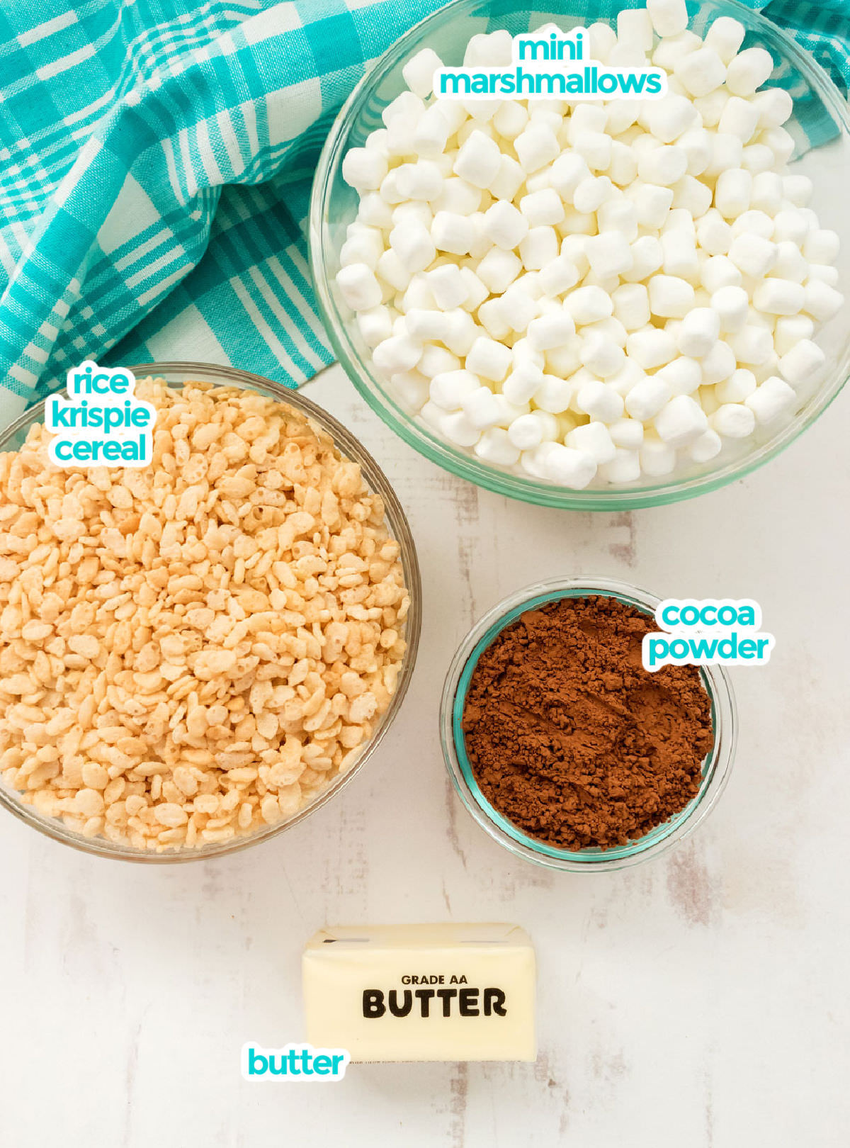All the ingredients you will need to make Chocolate Rice Krispie Treats including Mini Marshmallows, Rice Krispie Cereal, Butter and Cocoa Powder.