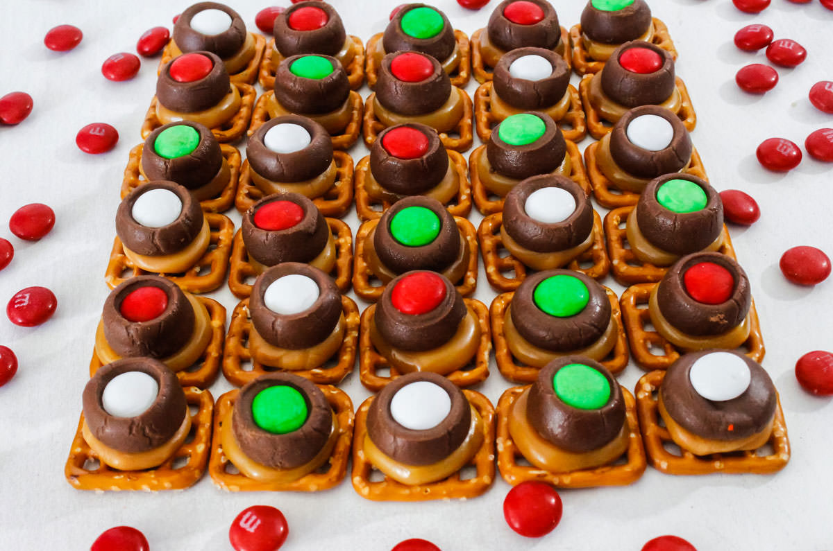 Closeup on a batch of Christmas Caramel Pretzel Bites arranged in rows on a white table.