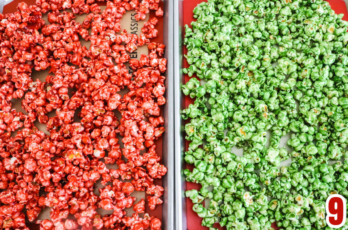 Overhead shot of a cookie sheet filled with red caramel corn and a second cookie sheet filled with green caramel corn.