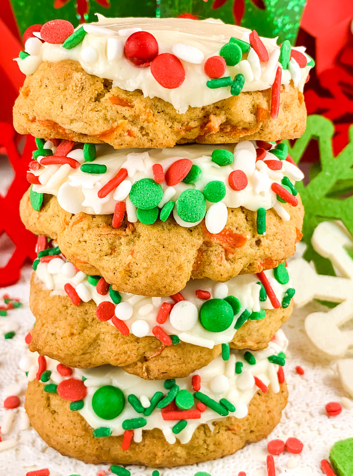 Close up on a stack of four Christmas Carrot Cake Cookies sitting on a white table in front on Christmas decorations.