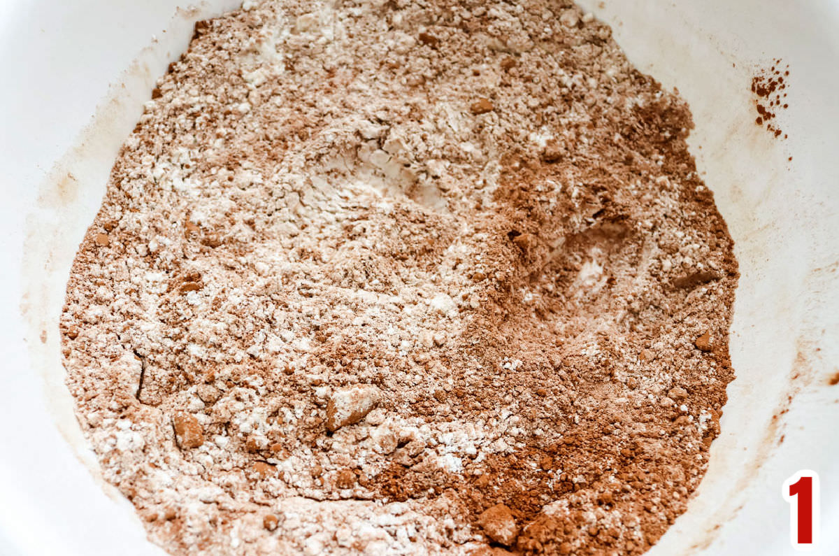 White mixing bowl filled with flour and  cocoa powder mixed together.