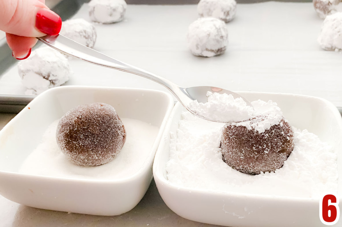 Image showing how to cover the chocolate cookie dough ball with granulated sugar and then powder sugar before baking.