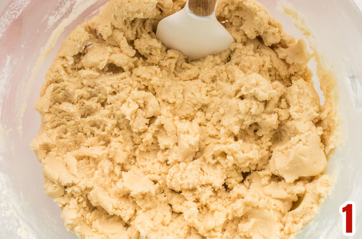 Closeup on a clear mixing bowl filled with Sugar Cookie dough.