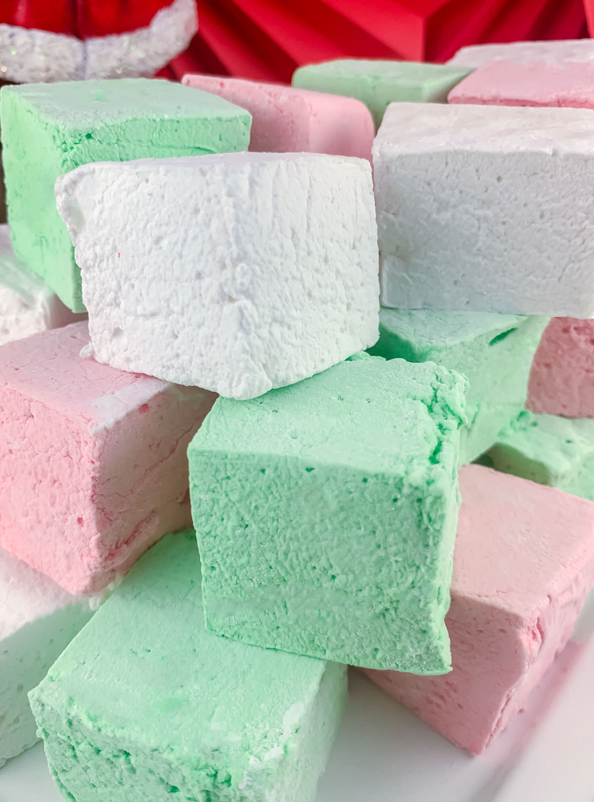 Closeup on a stack of Red, Green and White Christmas Homemade Marshmallows sitting on a white serving platter.