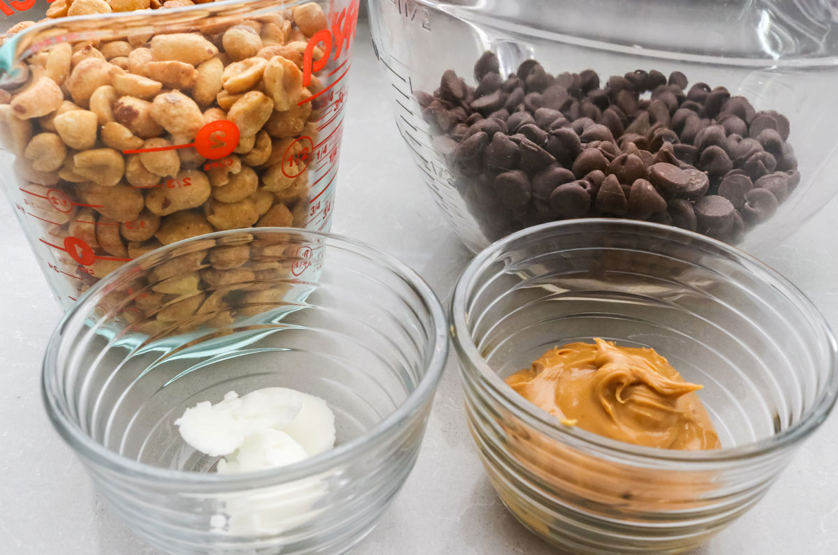 All the ingredients you will need to make Chocolate Peanut Clusters including Honey Roasted Peanuts, Chocolate Chips, Peanut Butter and Shortening.