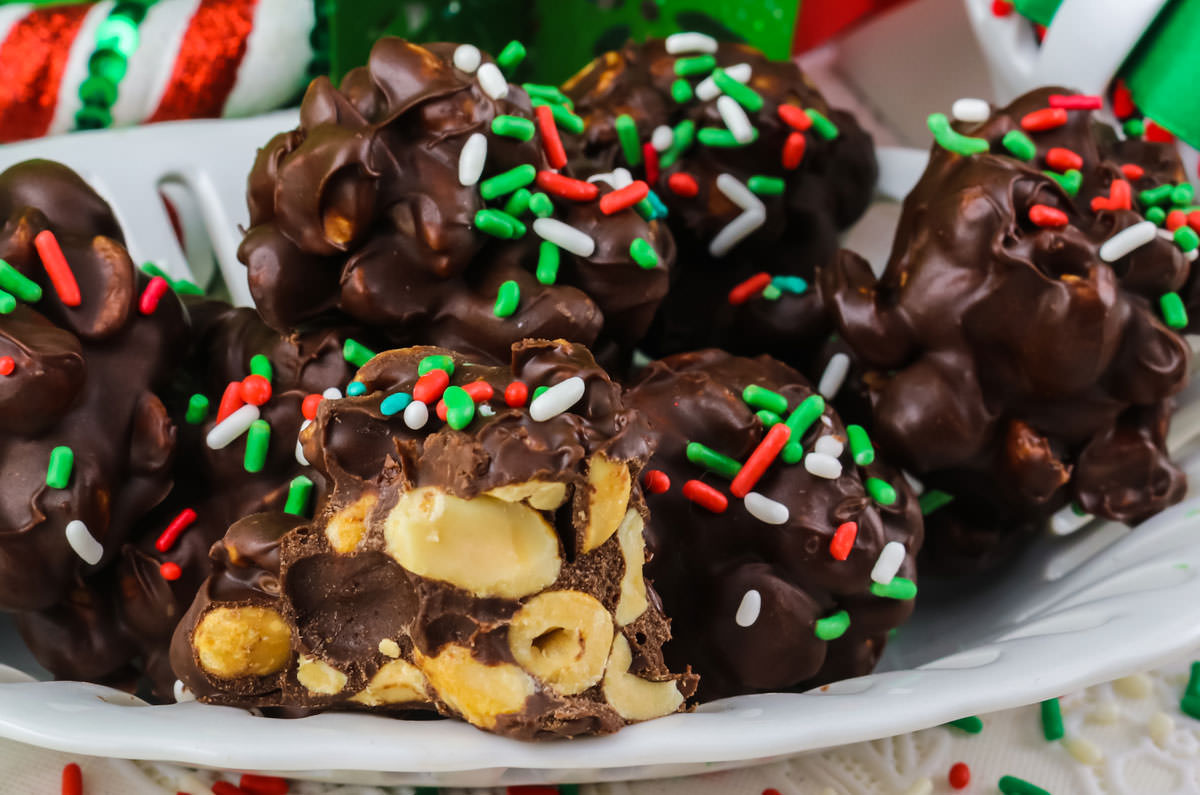 Closeup on a batch of Christmas Peanut Clusters on a white dessert dish.