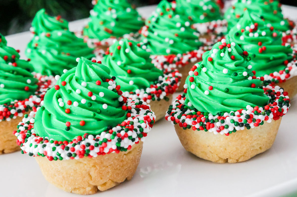 Closeup on a batch of Christmas Tree Cookie Cups on a white serving platter.
