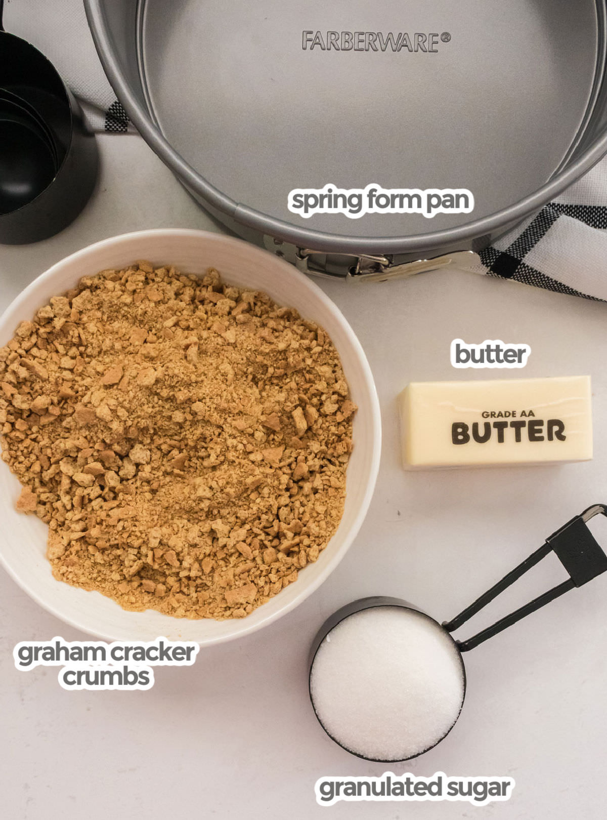All the ingredients required to make a Graham Cracker Crust including graham cracker crumbs, butter, sugar and a springform pan.