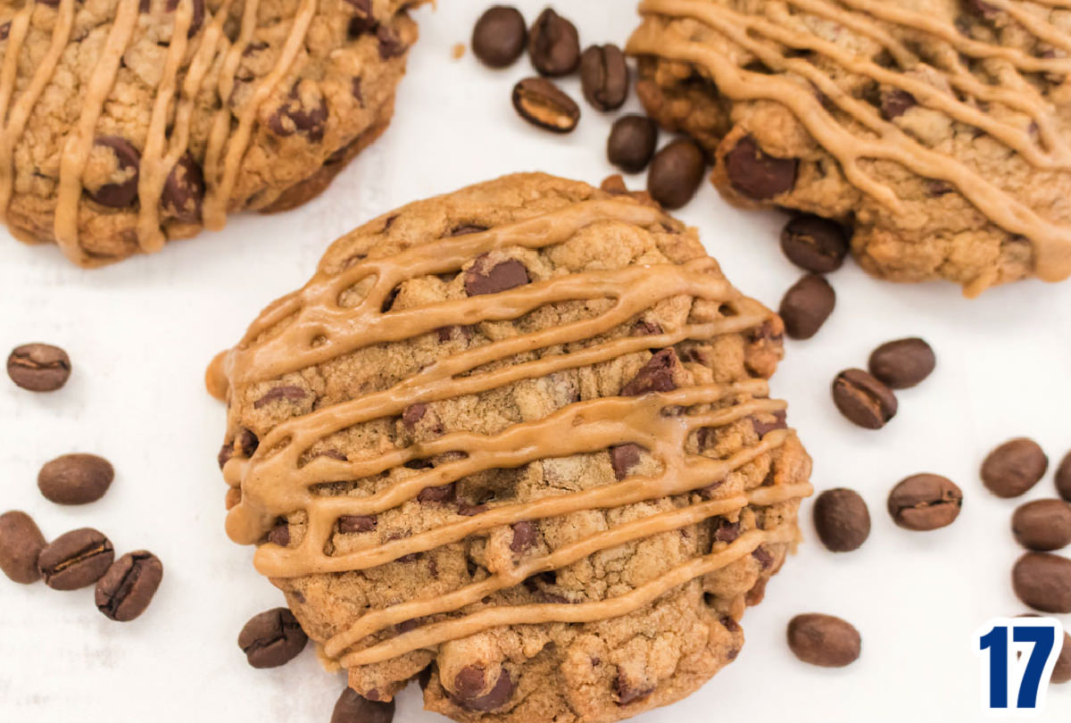 Closeup overhead shot of a Coffee Chocolate Chip Cookie with Coffee Icing sitting on a white table surrounded by coffee beans.