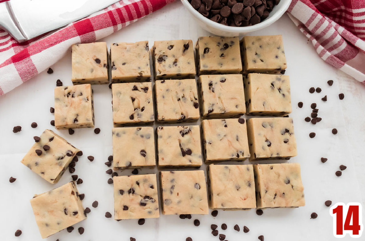 Overhead shot of twenty pieces of Cookie Dough Fudge arranged in rows on a white table surrounded by Mini Chocolate Chips.