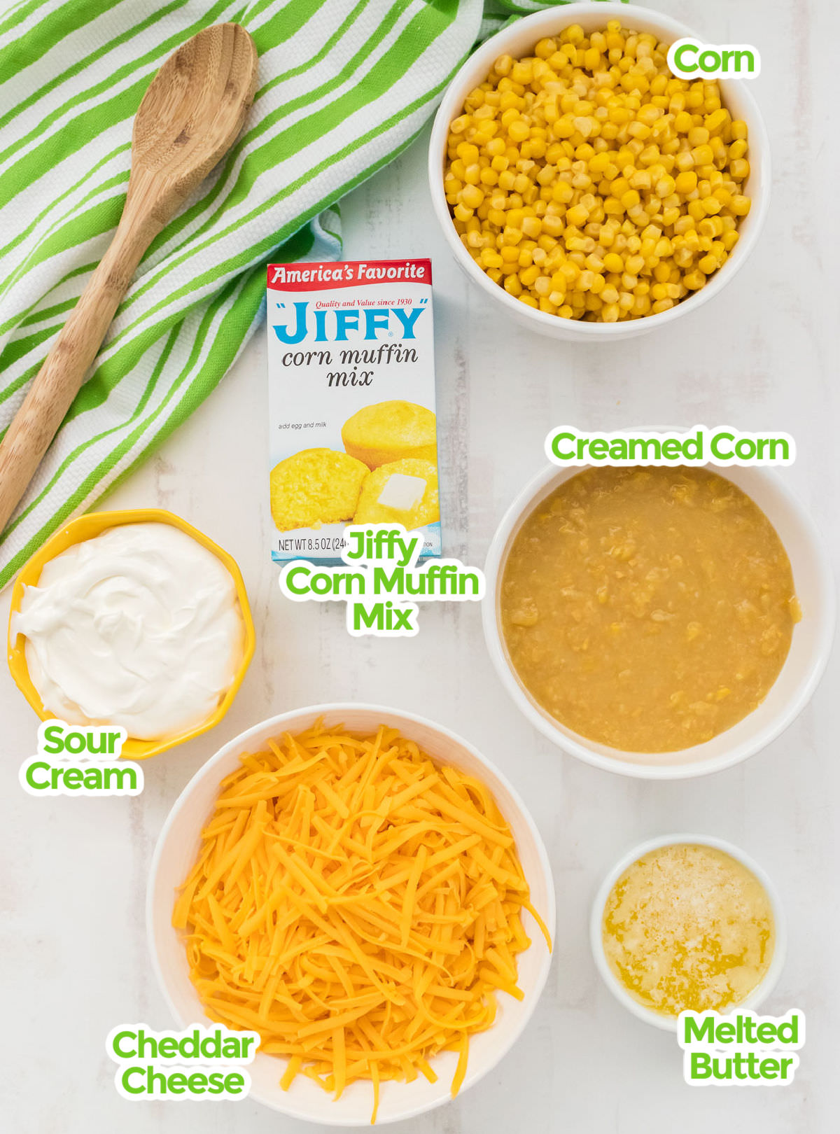 All the ingredients you will need to make Corn Casserole including Corn, Creamed Corn, Jiffy Corn Muffin Mix, Sour Cream, Melted Butter and Grated Cheddar Cheese.