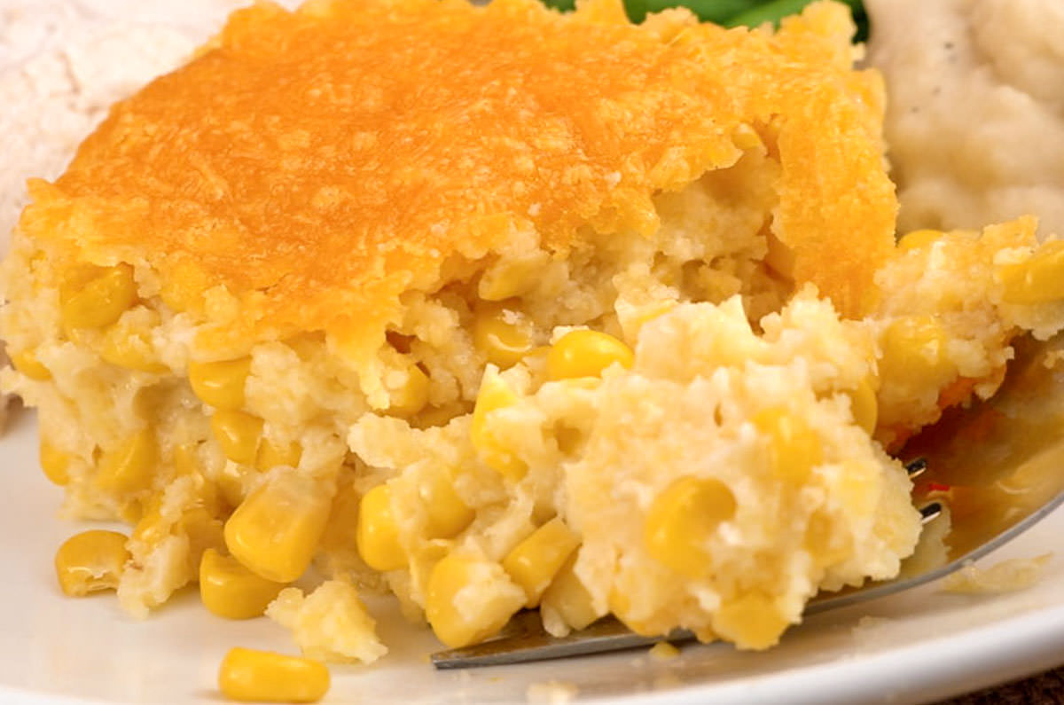 Closeup on a serving of Corn Casserole on a Thanksgiving dinner plate filled with turkey, mashed potatoes and vegetables.