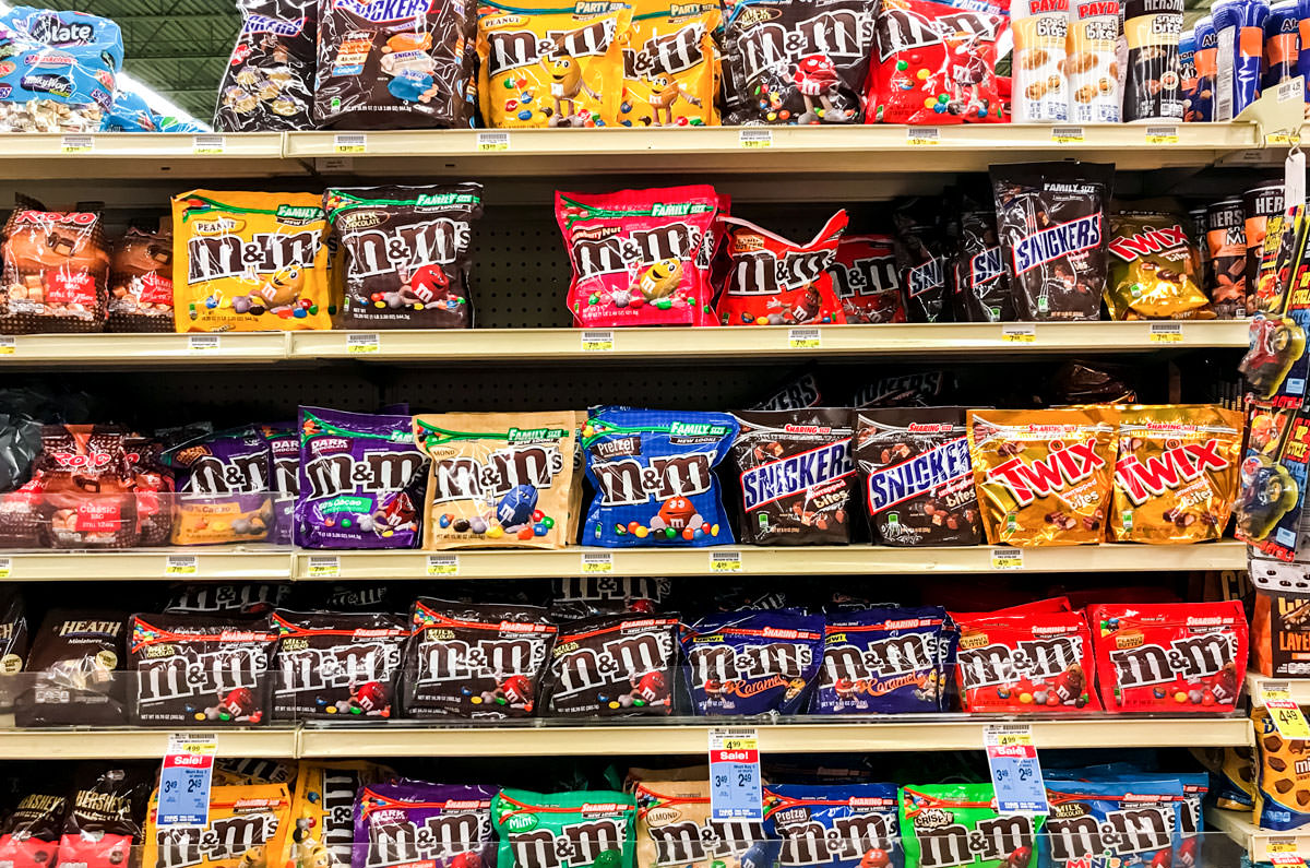A grocery store shelf filled with bags of different types of M&M's.