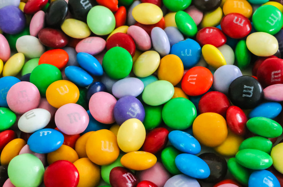 All the colors of M&M that are available for purchase spread out on a white table.