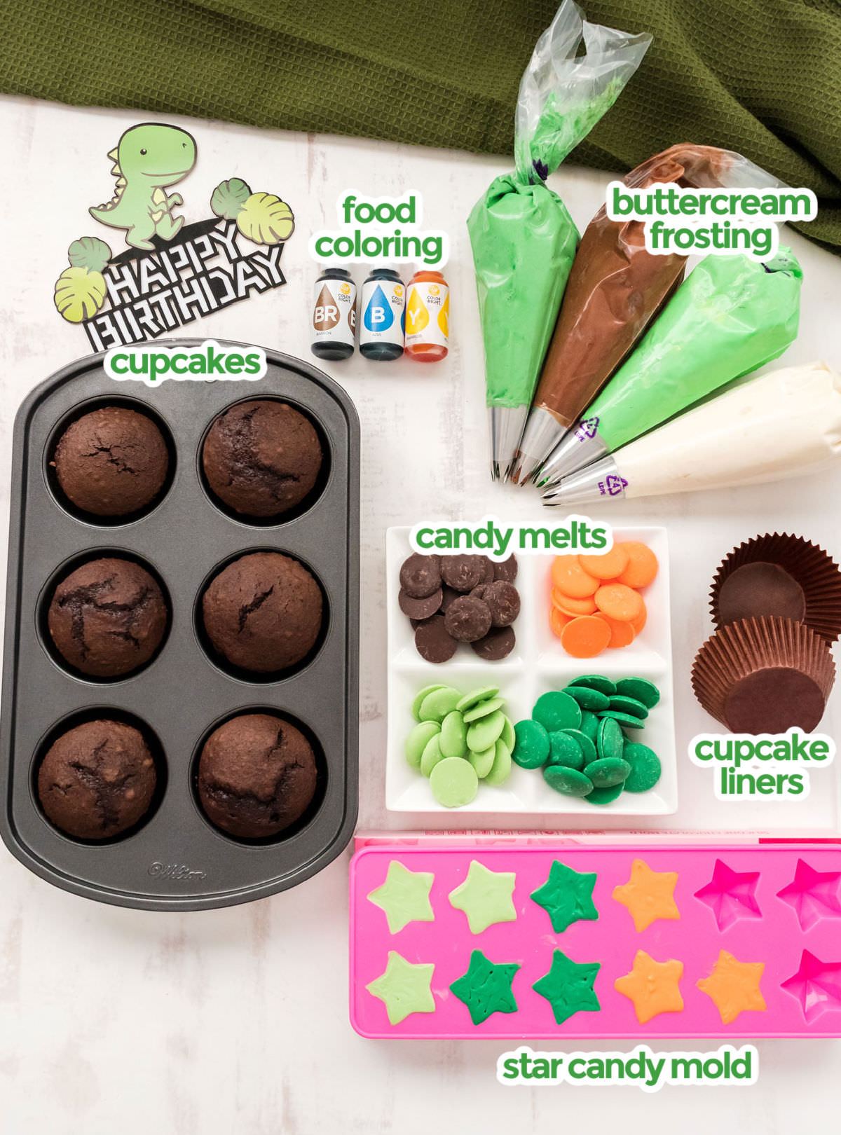All the ingredients you will need to make Dinosaur Cupcakes including cupcakes, buttercream frosting, candy melts, food coloring and a star candy mold.