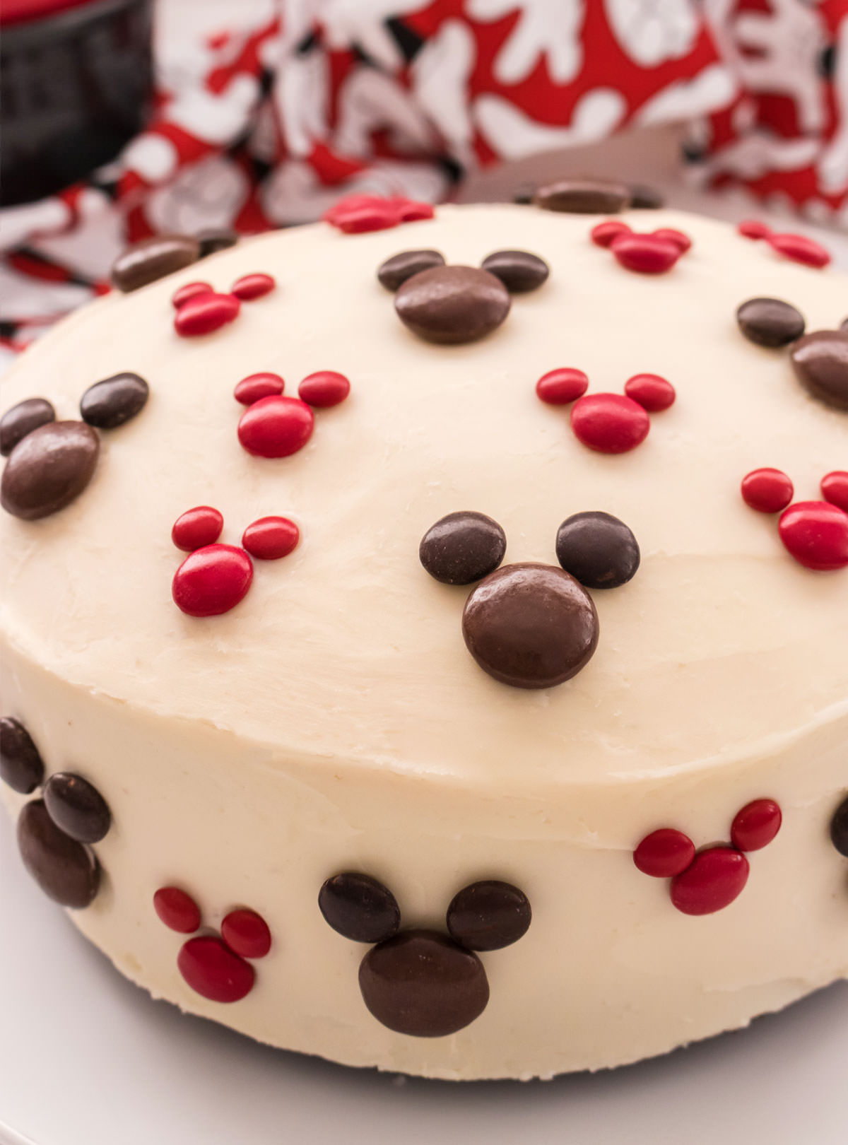 Closeup on an Easy Mickey Mouse Cake sitting on a white surface in front of a Mickey Mouse kitchen towel.