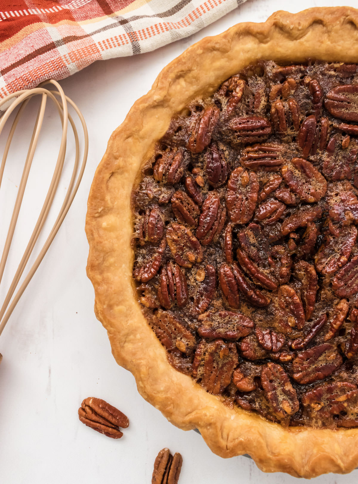 Picture showing half of a fully baked Pecan Pie on a white surface.