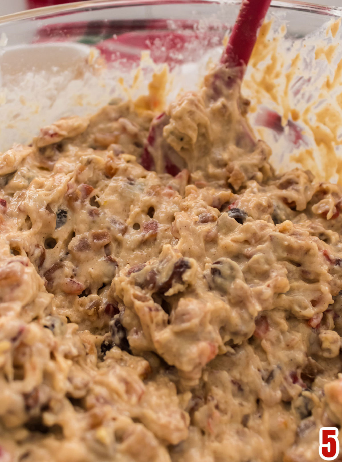 Closeup on a glass mixing bowl filled with Fruit Cake cake batter.