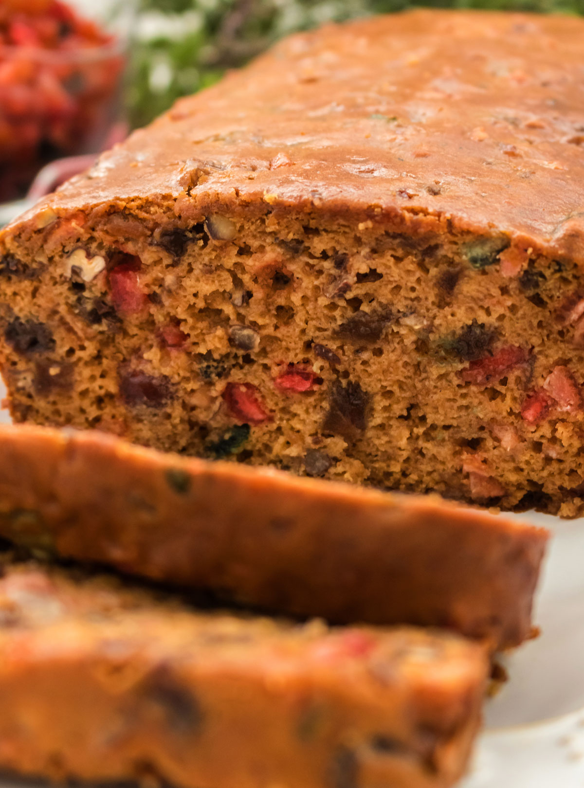 Closeup on a sliced loaf of The Best Fruit Cake on a white serving platter.