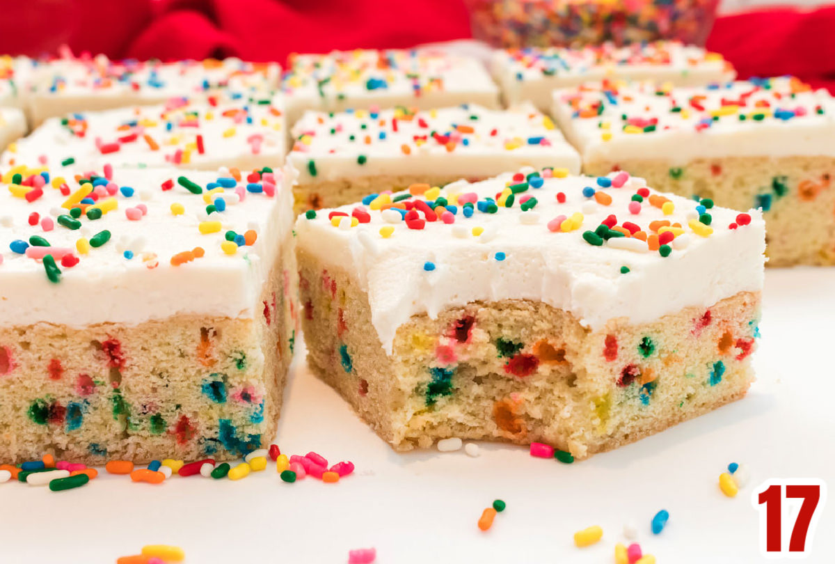 Funfetti Sugar Cookie Bars cut into individual bars arranged in rows on a white table with a red towel in the background.