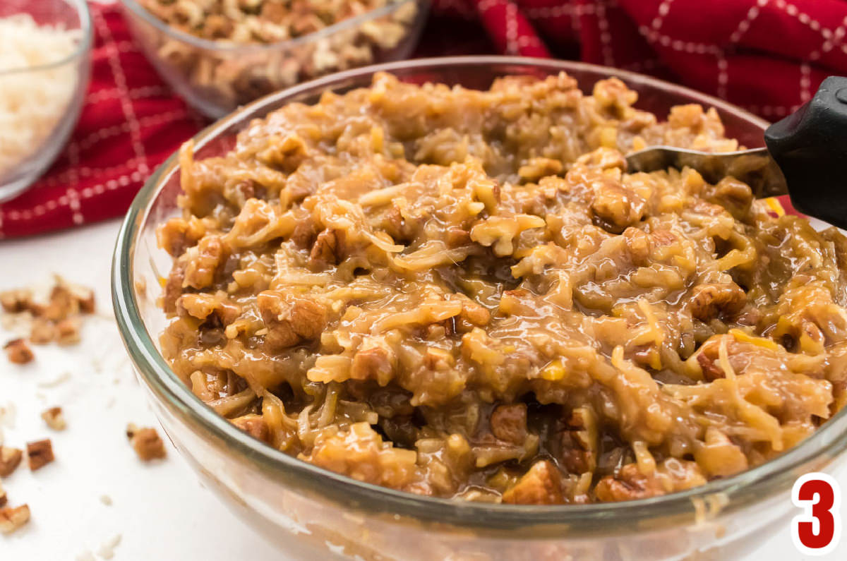 Closeup on a bowl of homemade Coconut Pecan Frosting in a glass bowl.