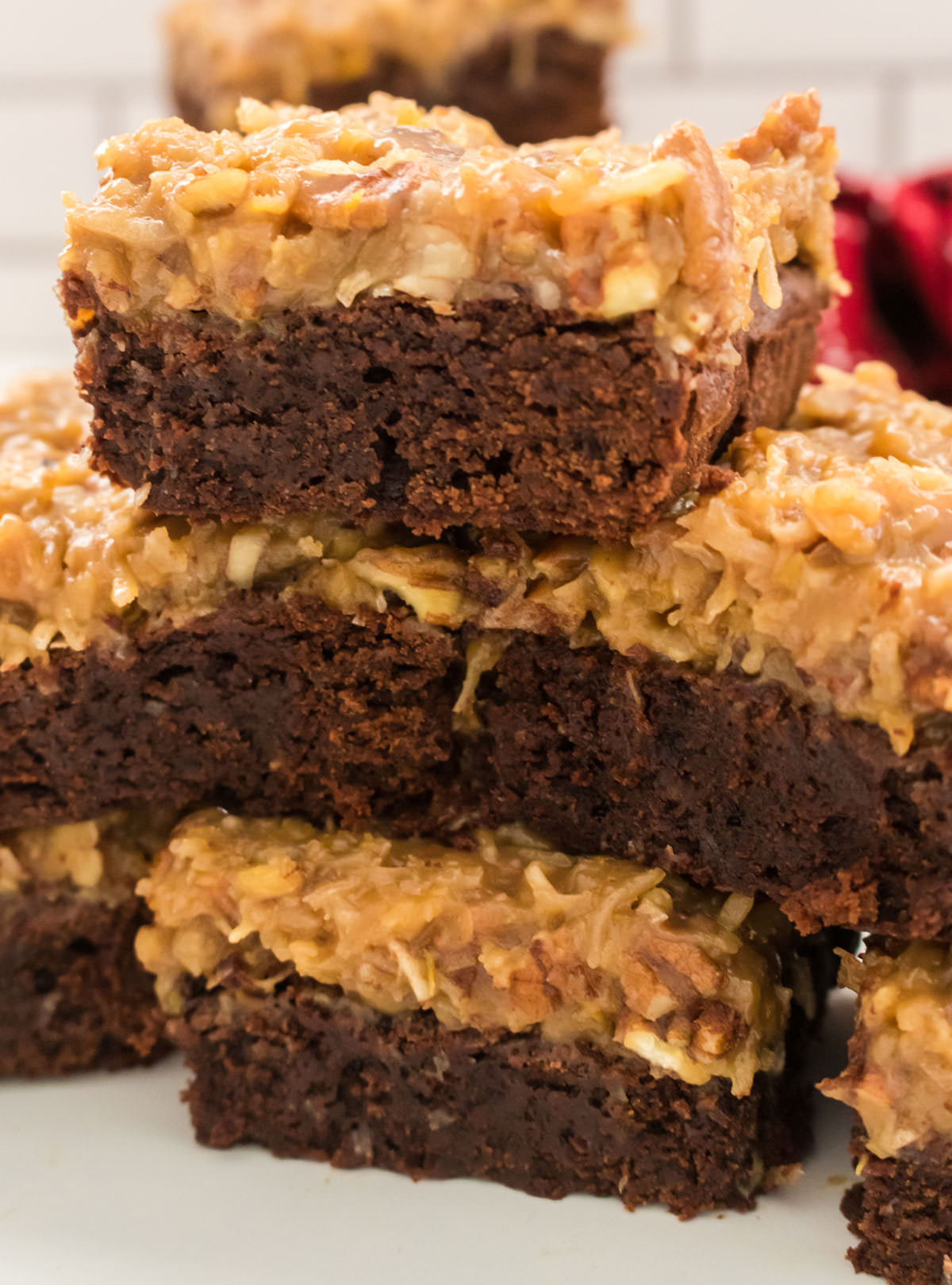 Closeup on a stack of German Chocolate Brownies sitting on a white table.