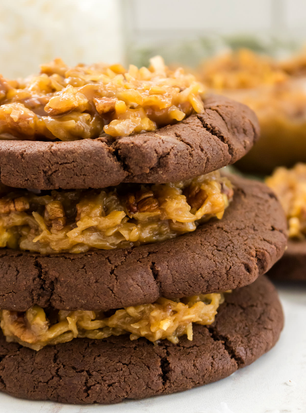 Closeup on a stack of German Chocolate Cookies sitting on a white table.