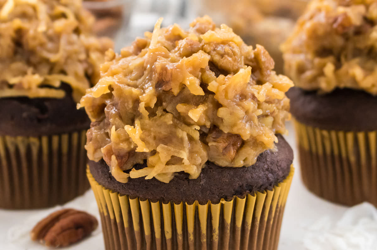 Closeup on three cupcakes topped with The Best German Chocolate Cake Frosting.