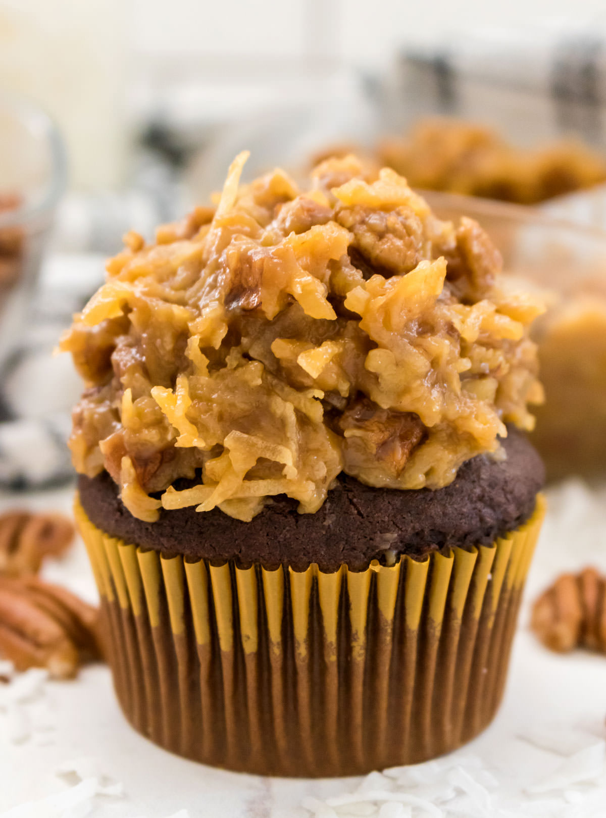 Closeup on a chocolate cupcake topped with The Best German Chocolate Cake Frosting.