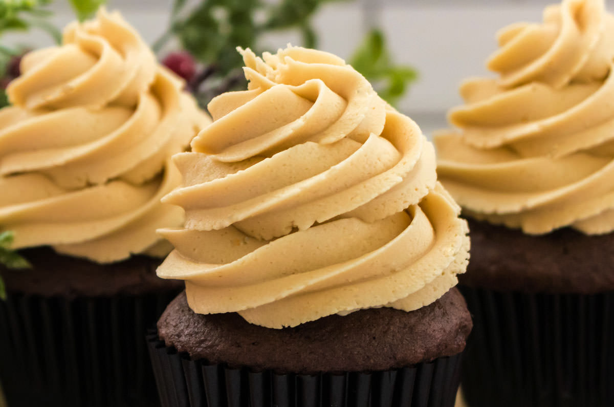 Closeup on three cupcakes topped with The Best Gingerbread Buttercream Frosting.